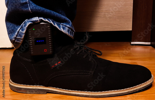 A close-up of a GPS tracking device on a man's leg, used by the police to monitor violent people
 photo