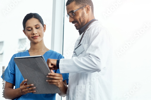 This patients vitals look good. two young doctors using a digital tablet in a modern hospital.