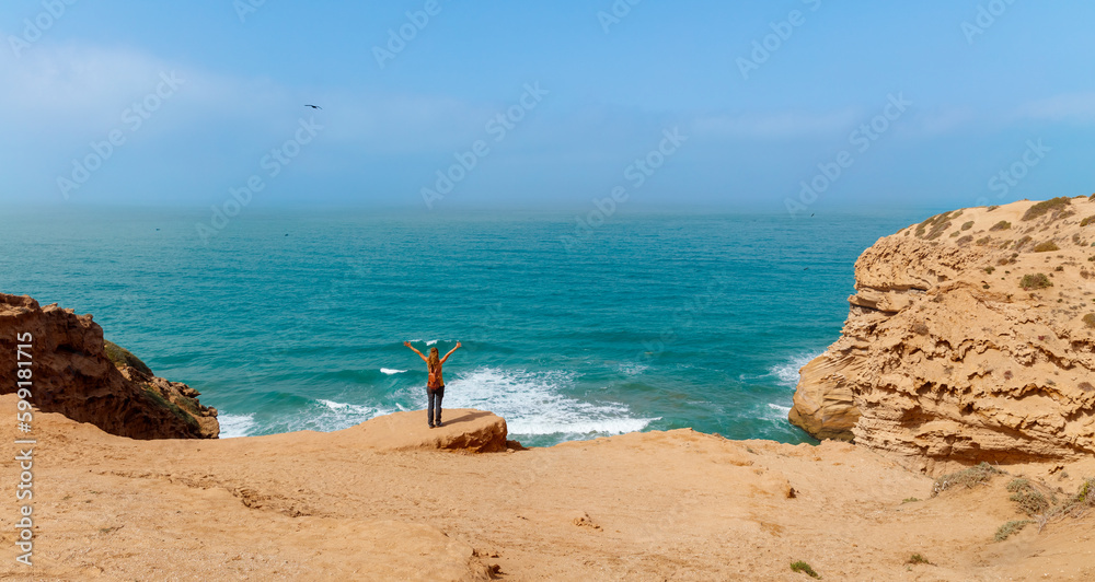Woman with flying hair in the wind in front of atlantic ocean- carefree,  freedom, vacation lifestyle concept