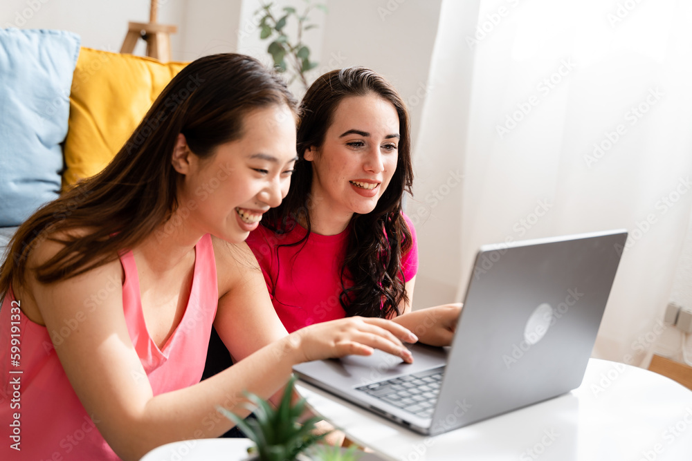 Two women using laptop in living room.