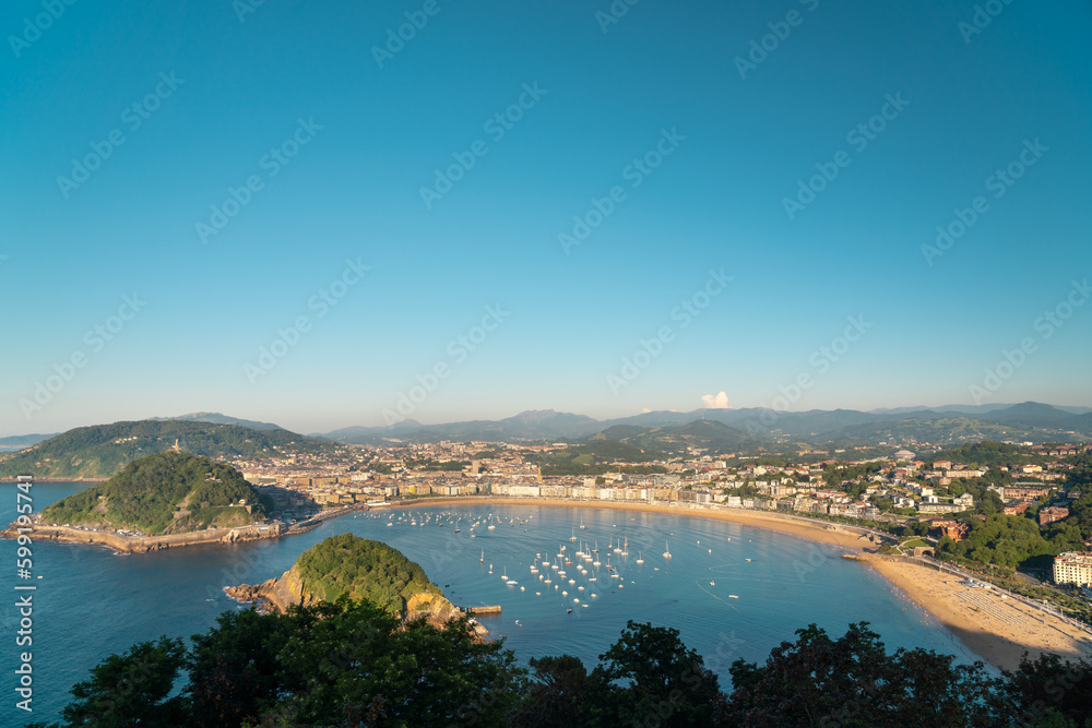 Fototapeta premium San Sebastian, SPAIN - July 09 2022: High angle view of San Sebastian - Donostia city at sunset. Situated in north of Spain, Basque Country. Famous travel destination. View of La Concha Bay