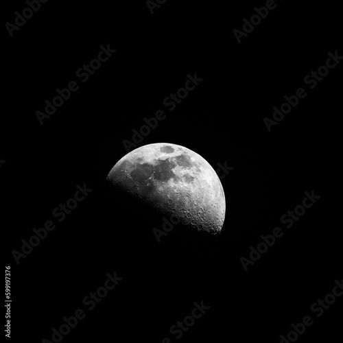 bright half of the moon lit in a dark background