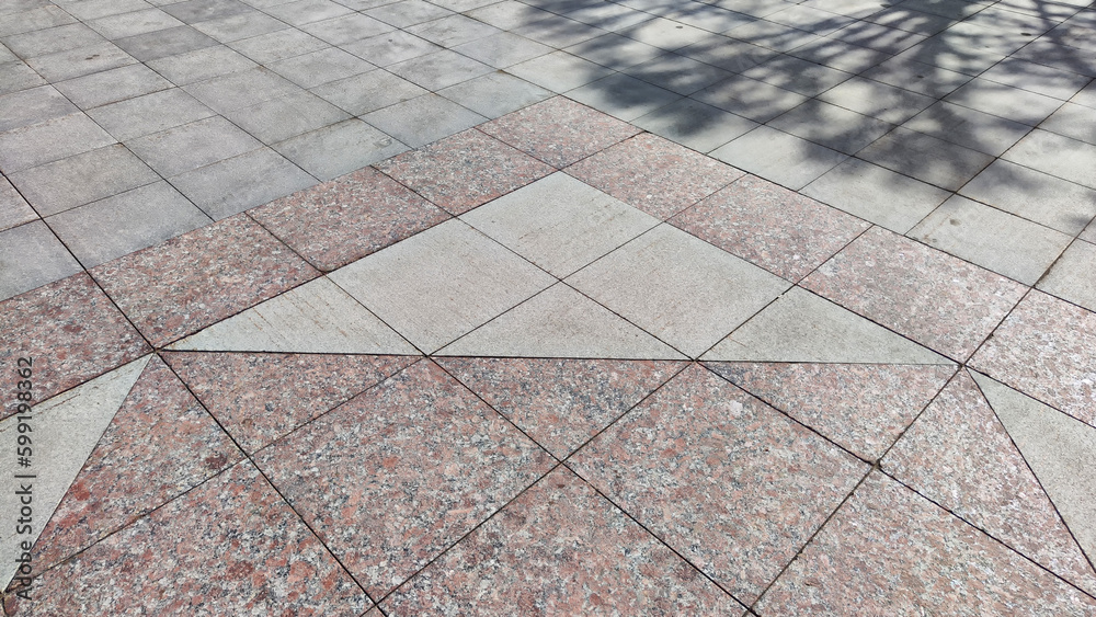 Fototapeta premium Gray tiles on the sidewalk in the city outdoors. Background and texture with lines and squares of tiles. Abstract frame, copy space, place for text