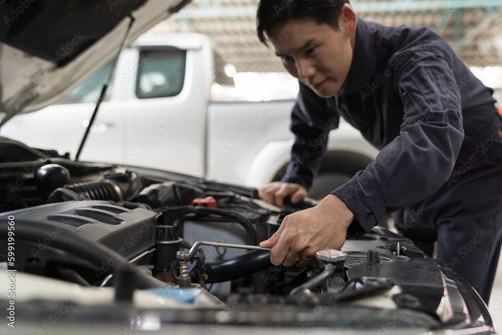 Car mechanic maintenance and auto service shop concept. Male car mechanic repair, fix car engine in auto repair shop. Technician inspecting quality parts of battery, electronic in garage workshop