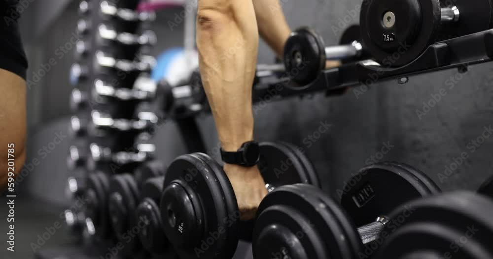 Male athlete with fitness watch on hand taking dumbbell for sports training in gym closeup 4k movie slow motion. Healthy lifestyle concept Male athlete with fitness watch on hand taking dumbbell for sports training in gym closeup 4k movie slow motion. Healthy lifestyle concept