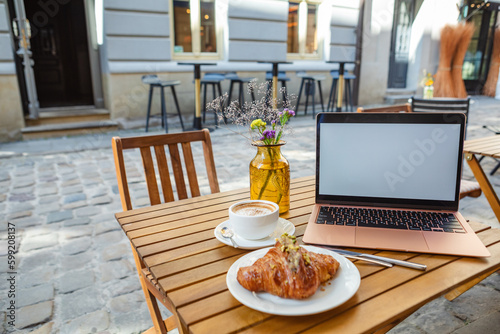 a freelancer's workplace in a cafe with a croissant and coffee