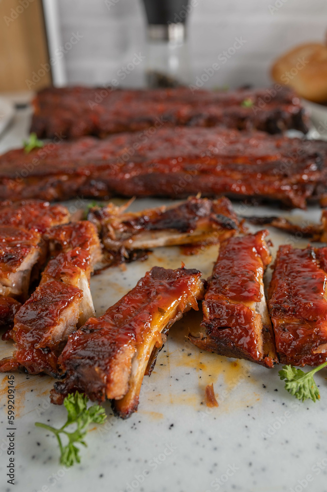 Fresh sliced pork ribs on a cutting board with whole ribs in the background