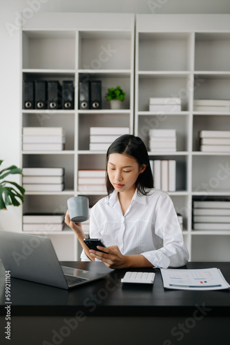 Asian businesswoman working in the modern office with working notepad, tablet and laptop documents