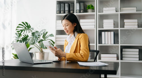 Asian businesswoman working in the modern office with working notepad, tablet and laptop documents