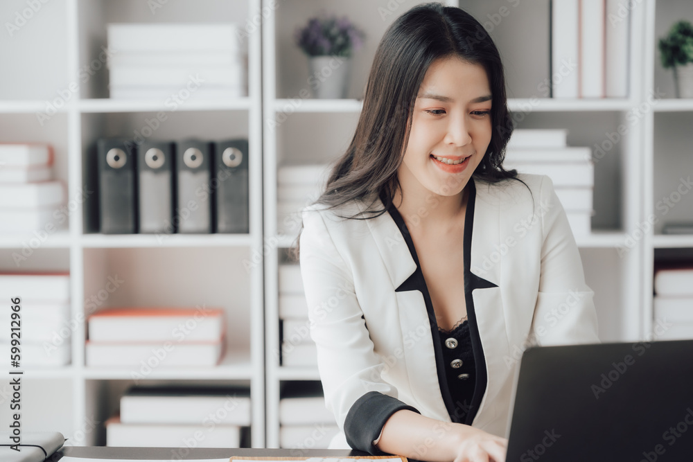 Cheerful business lady working on laptop in office, Asian happy beautiful businesswoman in formal suit work in workplace. Attractive female employee office worker smile. Cheerful business lady working on laptop in office, Asian happy beautiful businesswoman in formal suit work in workplace. Attractive female employee office worker smile.