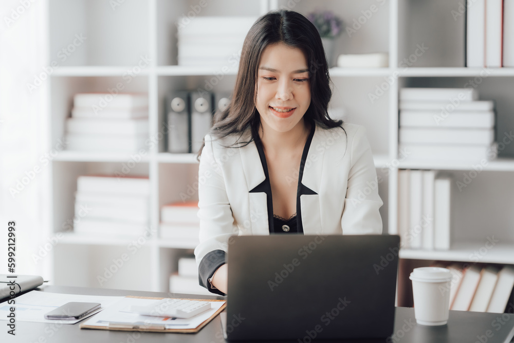 Cheerful business lady working on laptop in office, Asian happy beautiful businesswoman in formal suit work in workplace. Attractive female employee office worker smile. Cheerful business lady working on laptop in office, Asian happy beautiful businesswoman in formal suit work in workplace. Attractive female employee office worker smile.