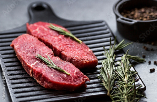 Fresh meat. Raw beef steaks with rosemary and spices on a stylish blackboard. Flat top view.
