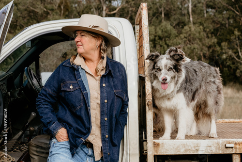 Mid fifties woman looking sideways with farm dogs on ute. photo