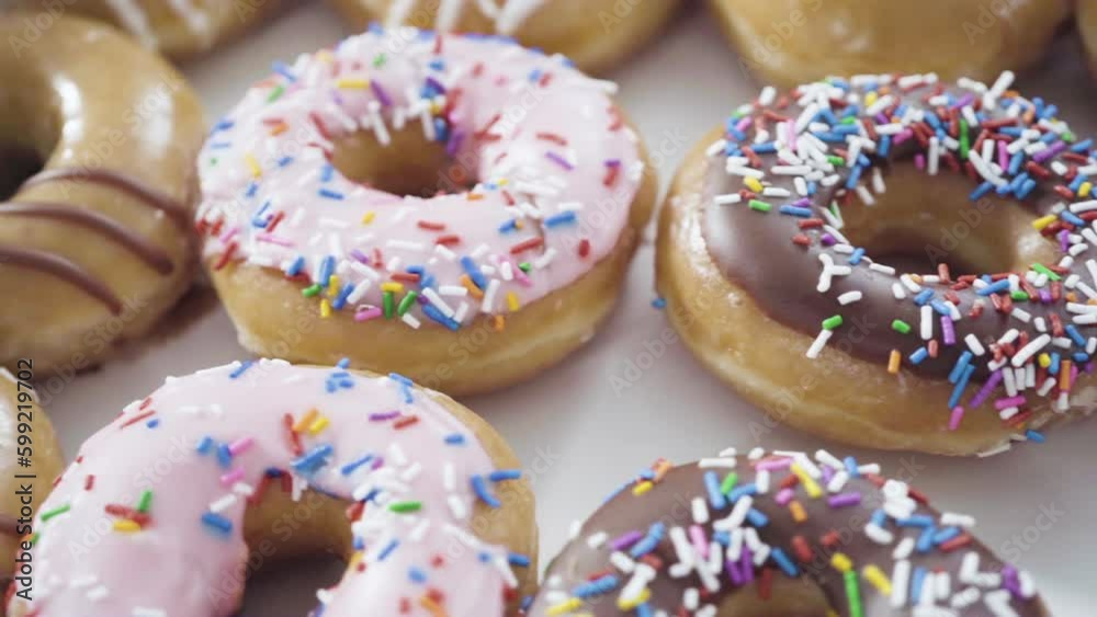 Variety of store-bought doughnuts in a white paper box.
