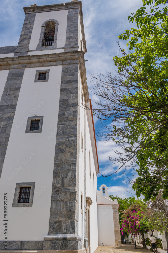 Bell tower and side view with bell of the Royal Basilica of Our Lady of Conceição next to the garden with flowers, Castro Verde - Alentejo PORTUGAL