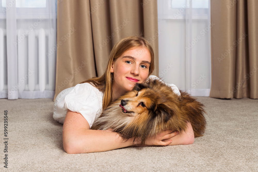 Adorable aged Miniature Sheltie dog and its owner, cute blonde girl are spending time together indoors. Strong friendship and funny leisure with the pet. Adorable aged Miniature Sheltie dog and its owner, cute blonde girl are spending time together indoors. Strong friendship and funny leisure with the pet.