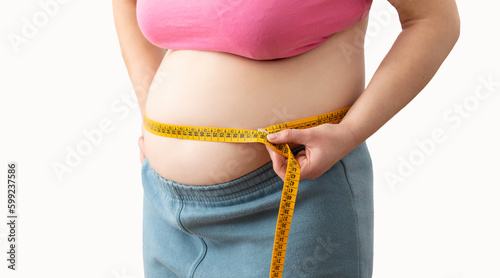 Obese woman measuring her waist with a measuring tape against a white background