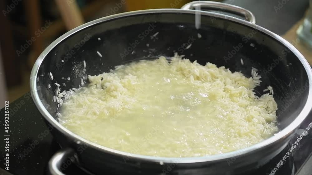 The chef adds chicken stock to the rice.
The chef adds chicken stock to the rice.