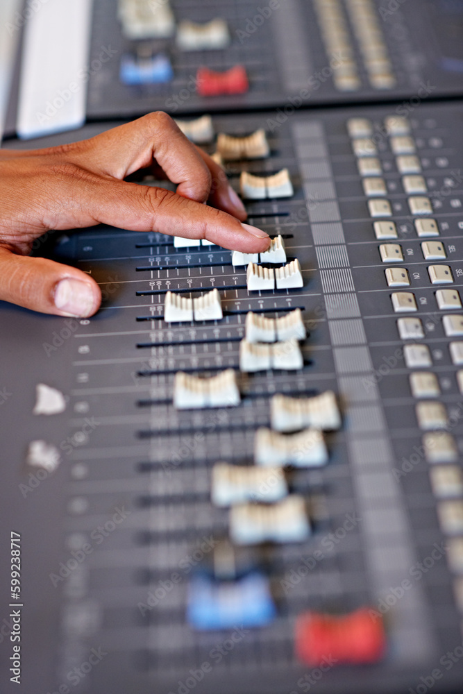 Adjusting the volume on a mix. Cropped close-up image of a hand moving a slider on a mixing desk. Adjusting the volume on a mix. Cropped close-up image of a hand moving a slider on a mixing desk.