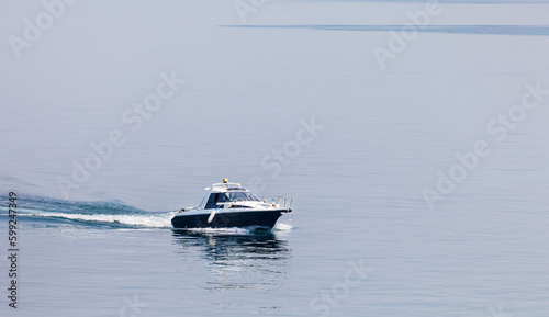 A pleasure boat moves along the sea surface of blue water on a foggy summer morning. Sea voyages, fishing, rest on the sea coast. Lake Baikal, Small Sea, Olkhon Island