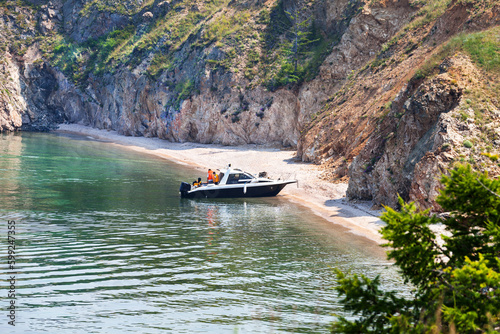 Baikal Lake on sunny summer day. Family of tourists with children travels along Small Sea on pleasure boat and moored to rest in cozy sandy bay of Olkhon Island. Summer travel and outdoor recreation