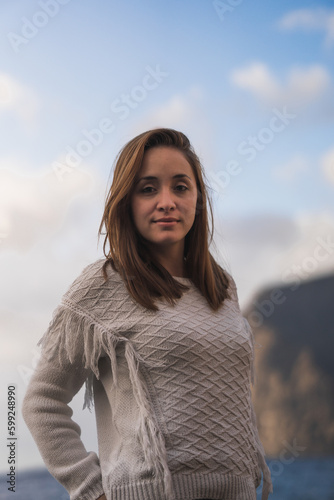 Caucasian woman with brown hair and white shirt on the beach at sunset.