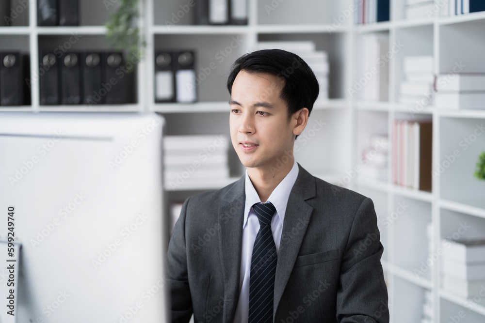 Young Asian businessman working at office with laptop and documents on table. Young Asian businessman working at office with laptop and documents on table.