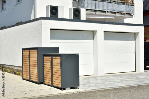 Luftwärmepumpe, Klimaanlage für Heizung und Warmwasser aufgebaut auf der Doppelgarage eines neu gebauten Wohnhaus sowie Geräteboxen vor der Garage