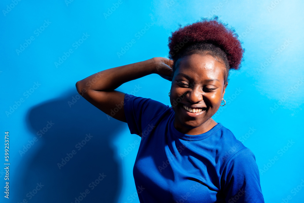 Young african american woman isolated on a blue background smiling and dancing, studio shoot Young african american woman isolated on a blue background smiling and dancing, studio shoot