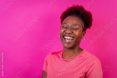 Young african american woman isolated on a pink background smiling and laughing, studio shoot