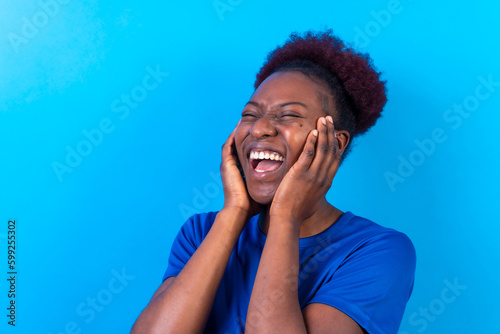 Young african american woman isolated on a blue background smiling and laughing, studio shoot