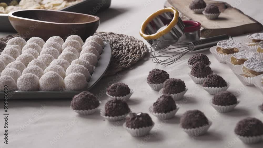 Dolly movement on pastry table with: Brazilian brigadeiro sweets in white and dark chocolate, Chilean alfajores with leaves and delicacy