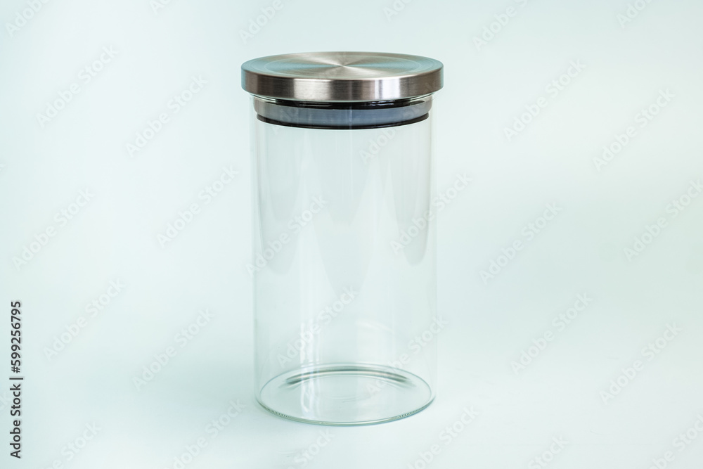 Glass transparent jar for bulk products with a vacuum lid on a pale green background. Glass jar with stainless steel lid with silicone seal. Glass transparent jar for bulk products with a vacuum lid on a pale green background. Glass jar with stainless steel lid with silicone seal.