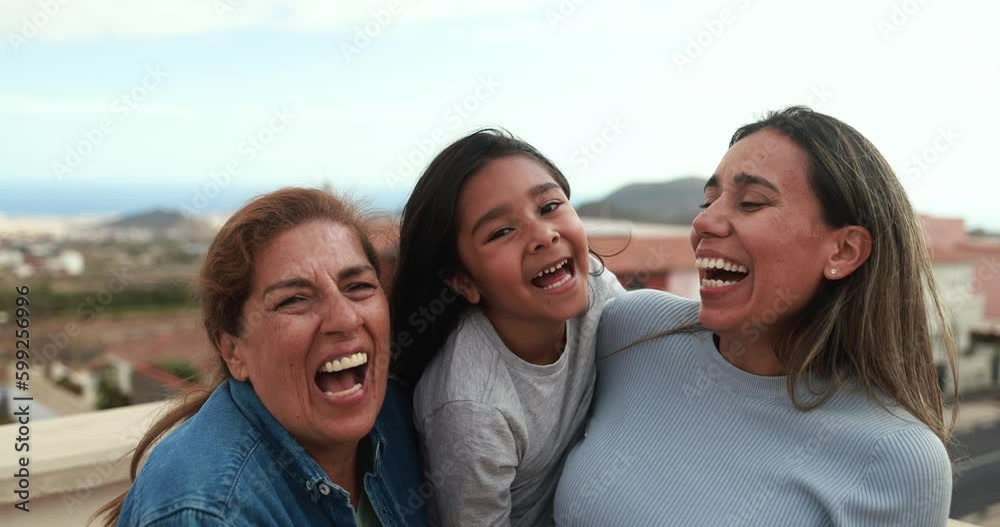 Happy latin multi generational family having fun together while smiling on camera at house rooftop