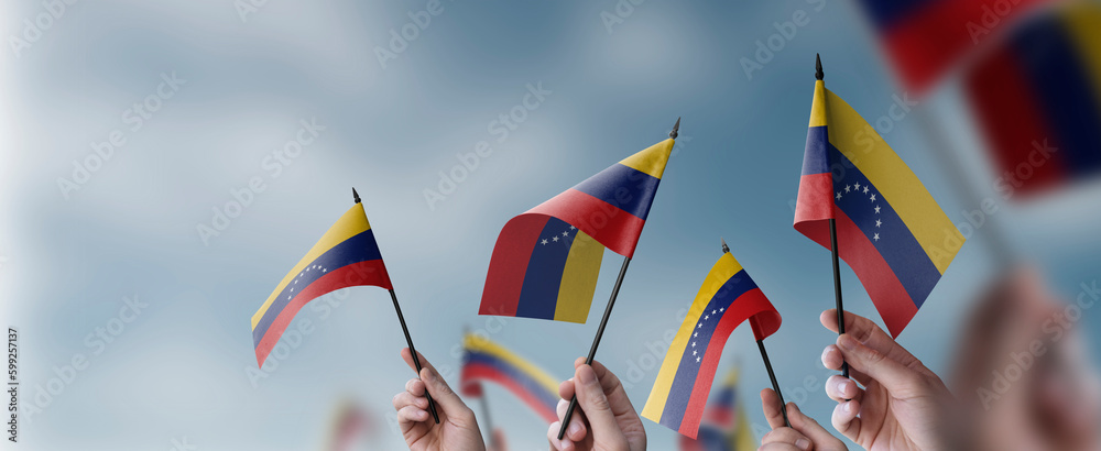 A group of people holding small flags of the Venezuela in their hands A group of people holding small flags of the Venezuela in their hands
