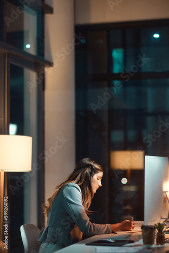 Shes the epitome of career dedication. a young businesswoman using a computer during a late night at work.