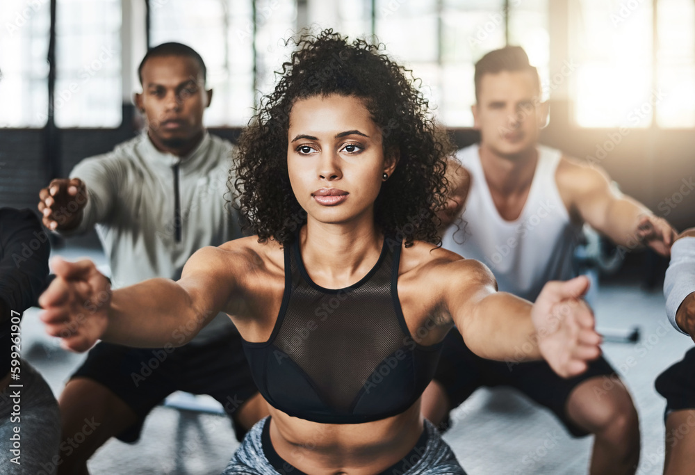 Building those lower body muscles. a group of young people doing squats together during their workout in a gym. Building those lower body muscles. a group of young people doing squats together during their workout in a gym.