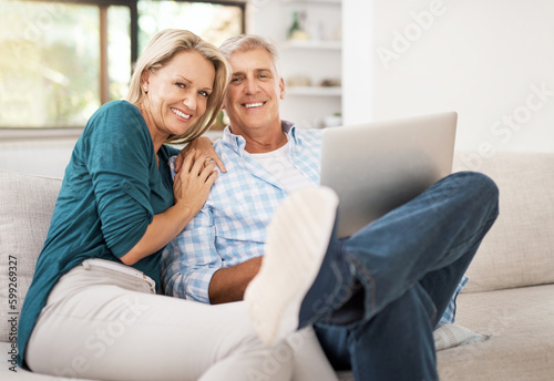 We enjoy watching our shows together. Portrait of an affectionate mature couple using a laptop while sitting on the sofa together at home. © Jadon Bester/peopleimages.com
