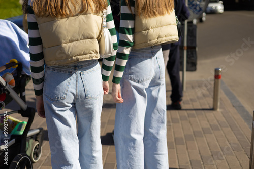 twins girls wearing same clothes are walking down the street 