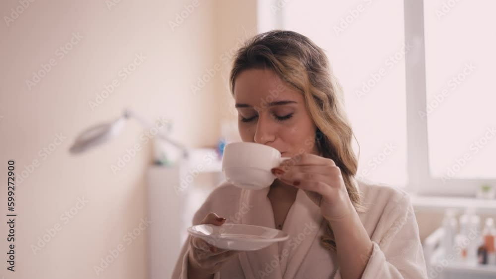 Young woman drinking coffee while waiting for her appointment with beautician Young woman drinking coffee while waiting for her appointment with beautician