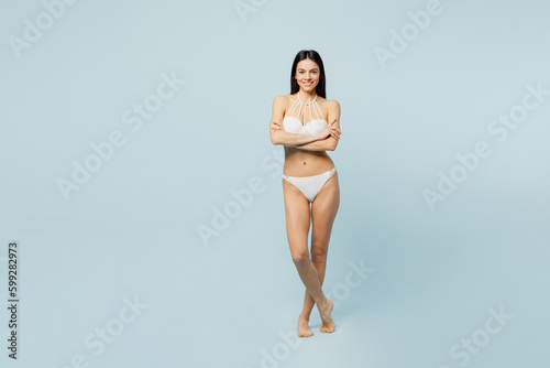 Full body smiling happy young woman wear swimsuit near hotel pool hold hands crossed folded look camera isolated on plain pastel light blue cyan background. Summer vacation sea rest sun tan concept.