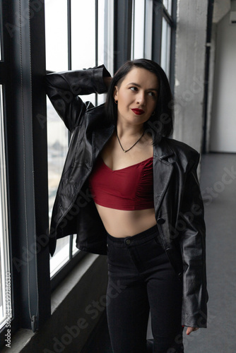 Girl in red top and leather jacket by the window