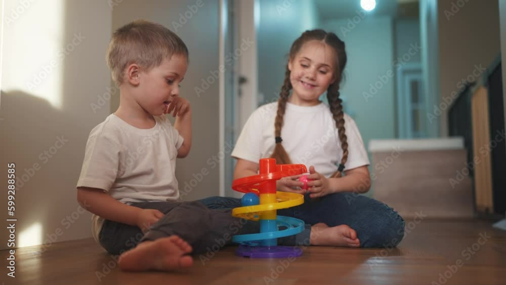 children baby play together toys in kindergarten. happy family preschool education indoor concept. baby boy and girl play toy roll a ball down a slide on lifestyle the floor rejoice in kindergarten children baby play together toys in kindergarten. happy family preschool education indoor concept. baby boy and girl play toy roll a ball down a slide on lifestyle the floor rejoice in kindergarten