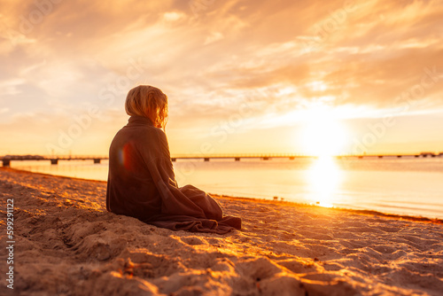 Girl (8-9) sitting on beach at sunset