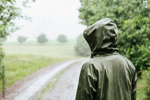 Rear view of woman in green raincoat standing in rain photo