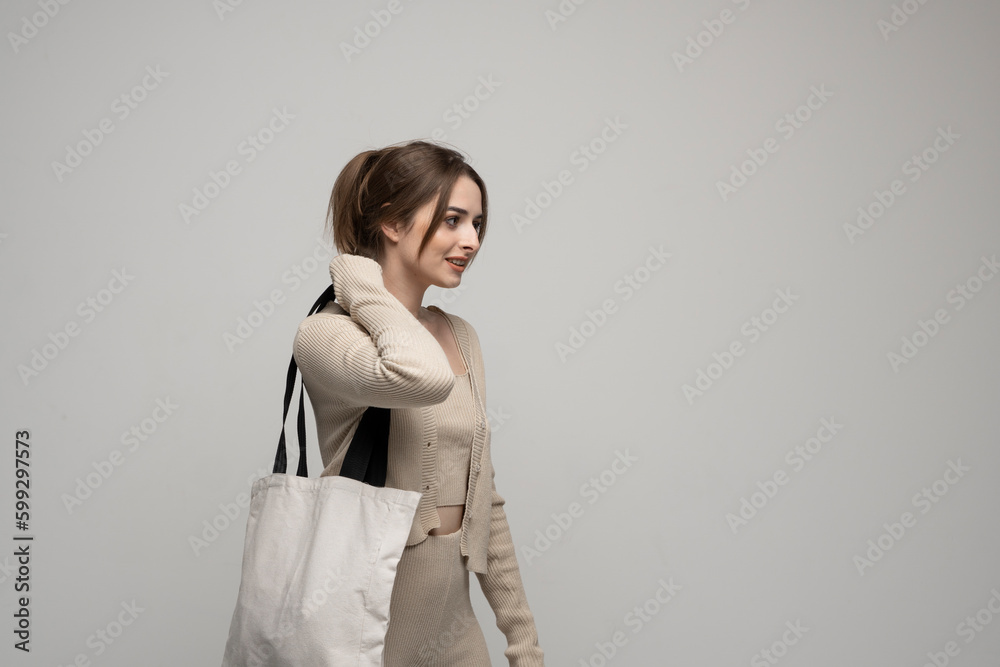 Happy, smiling brunette young woman carrying reusable cotton bag. Concept of recycle for better environment. No plastic. Happy, smiling brunette young woman carrying reusable cotton bag. Concept of recycle for better environment. No plastic.