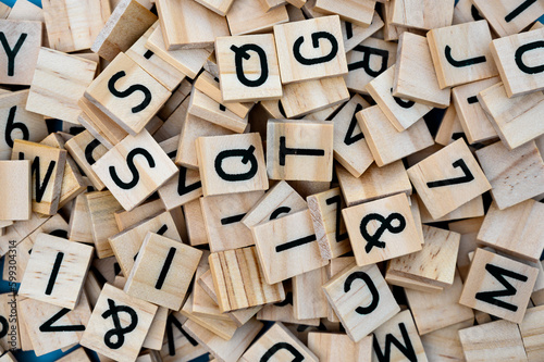 Background from wooden letters of the alphabet randomly scattered. Top view of a square wooden tile with the English alphabet. The concept of the development of thinking, grammar.