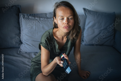 Foto Pretty, young woman sitting on the sofa indoors at home and watching TV