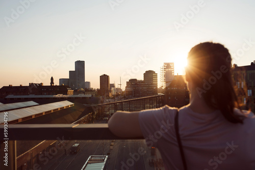 Woman looking at city at sunset