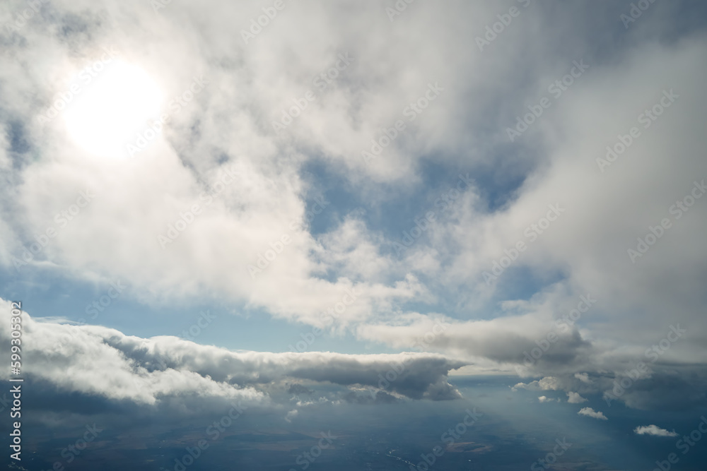 Aerial view from airplane window at high altitude of earth covered with puffy cumulus clouds forming before rainstorm